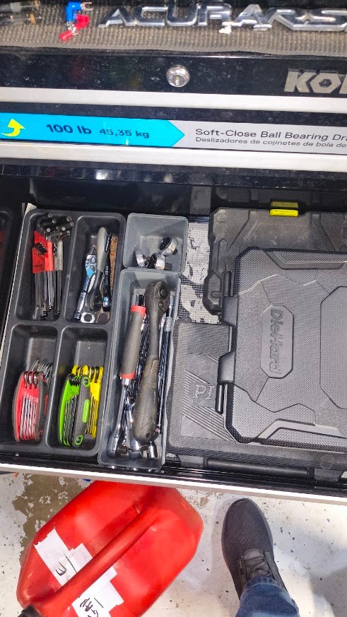Open automotive tool drawer with organized hand tools and tool cases